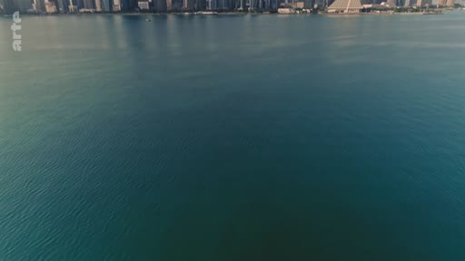 Vue aérienne panoramique de la baie de Doha au Qatar, montrant le littoral urbain avec ses gratte-ciels en arrière-plan et les eaux calmes du golfe Persique.
