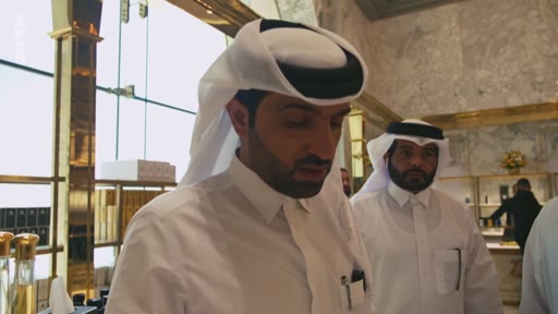Deux hommes en tenue traditionnelle qatarienne, dont un portant une ghutra, visitent une boutique de luxe avec des étagères dorées. La scène se déroule dans un environnement élégant, probablement à Doha, au Qatar.