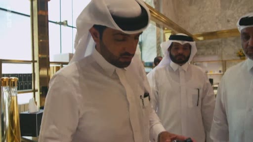Des hommes portant la thobe et le ghutra visitent une boutique de parfums ou de produits de luxe au Qatar, dans un cadre élégant avec des présentoirs dorés.