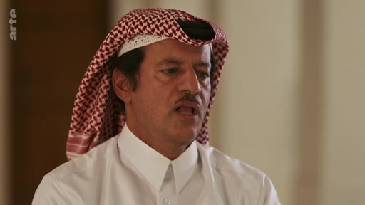 Un homme en tenue traditionnelle arabe, portant une ghutra, est filmé en gros plan lors d'une interview télévisée. Il s'exprime face caméra dans un cadre formel.