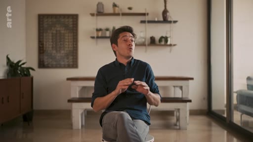 Un homme s'exprime lors d'une interview dans un intérieur moderne, dans le cadre du documentaire sur la révolution de palais de 1995.