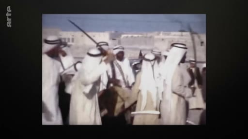 Des hommes en tenue traditionnelle, portant des thobes et des ghutras, participent à une danse traditionnelle avec des sabres lors d'une cérémonie publique. Cette séquence d'archives illustre les traditions culturelles au Qatar.