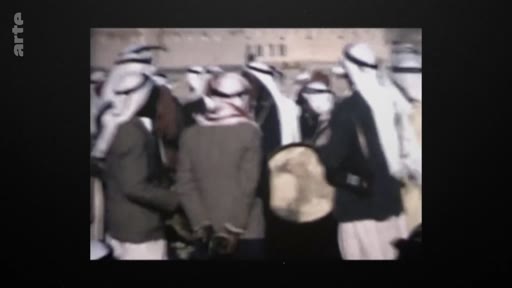 Des hommes vêtus de keffiehs traditionnels sont réunis en extérieur, probablement lors d'un rassemblement politique ou social au Moyen-Orient, capturé dans une archive historique.