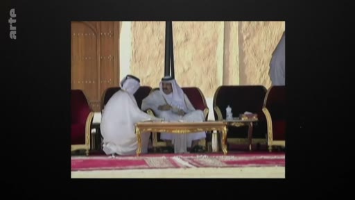 Deux hommes vêtus de thobes et de ghutras, tenues traditionnelles du Qatar, sont assis sur des fauteuils et discutent autour d'une table basse dorée dans un espace extérieur. Cette image d'archive montre une rencontre formelle ou diplomatique dans un contexte qatarien.