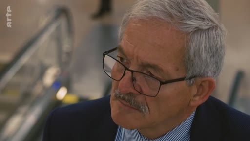 Gros plan sur un homme âgé aux cheveux gris, portant des lunettes et une moustache, lors d'une interview télévisée. Le logo de la chaîne Arte est visible dans le coin supérieur gauche.