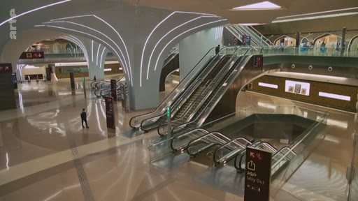 Vue d'ensemble de l'architecture moderne et lumineuse de la station de métro Msheireb à Doha, au Qatar, avec ses escalators et ses espaces de circulation spacieux.