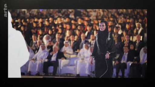 La Sheikha Moza bint Nasser, figure influente du Qatar, est photographiée lors d'une apparition publique devant une assemblée nombreuse. Elle porte une tenue traditionnelle élégante dans un cadre formel.