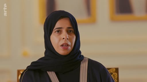 Une femme portant un hijab noir s'exprime face caméra lors d'une interview télévisée. Elle est filmée en gros plan dans un cadre formel, probablement dans le cadre d'un reportage sur les enjeux sociaux ou politiques au Moyen-Orient.