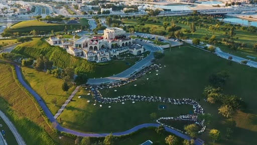 Vue aérienne du Katara Cultural Village à Doha, au Qatar, montrant l'architecture traditionnelle et les espaces verts environnants. Ce site emblématique est un centre culturel majeur accueillant des événements et des festivals.