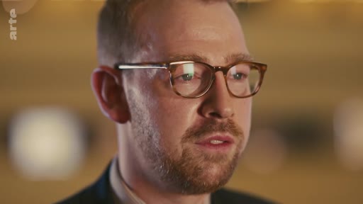 Un homme barbu portant des lunettes est filmé en gros plan lors d'une interview télévisée. Le logo de la chaîne Arte est visible dans le coin supérieur gauche.