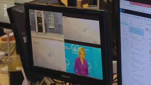 Un écran de contrôle dans une salle de rédaction montre des images en direct de 10 Downing Street et une conférence de presse avec une porte-parole, probablement Maria Zakharova, devant le logo du ministère des Affaires étrangères russe.