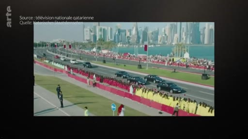 Un cortège de voitures officielles circule le long de la corniche de Doha, au Qatar, devant une foule rassemblée derrière des barrières. L'image provient des archives de la télévision nationale qatarienne.