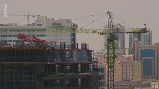 Vue extérieure d'un chantier de construction urbain avec une grue à tour et des structures en béton en cours d'édification. Le paysage urbain en arrière-plan montre des immeubles modernes, illustrant le développement immobilier et l'urbanisation.