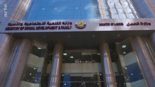 Vue extérieure du bâtiment abritant le ministère du Développement social et de la Famille et le ministère du Travail au Qatar. Le bâtiment affiche les noms des deux institutions en arabe et en anglais sur sa façade.