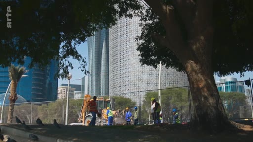 Des ouvriers en tenue de chantier travaillent sur un site de construction à Doha, au Qatar, avec les tours emblématiques du quartier d'affaires en arrière-plan. La scène montre l'urbanisation rapide et les projets de développement immobilier dans la capitale qatarie.