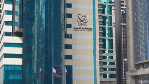 Vue extérieure du bâtiment abritant le siège de l'agence de presse officielle Qatar News Agency (QNA) à Doha, au Qatar, avec le logo de l'institution visible sur la façade.