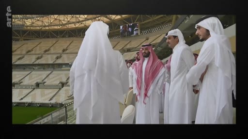 Le prince héritier saoudien Mohammed ben Salmane et l'émir du Qatar Tamim ben Hamad Al Thani visitent un stade de football au Qatar, probablement en marge de la Coupe du monde 2022. Ils sont entourés d'autres officiels portant la tenue traditionnelle.