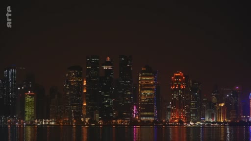 Vue panoramique nocturne de la skyline de Doha, capitale du Qatar, avec ses gratte-ciels illuminés se reflétant dans les eaux du golfe Persique.