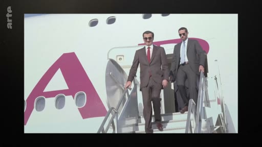 L'émir du Qatar, Tamim ben Hamad Al Thani, descend les escaliers d'un avion privé portant le logo de Qatar Airways, accompagné d'un garde du corps ou conseiller. Cette image illustre les déplacements officiels et la diplomatie internationale du dirigeant qatarien.