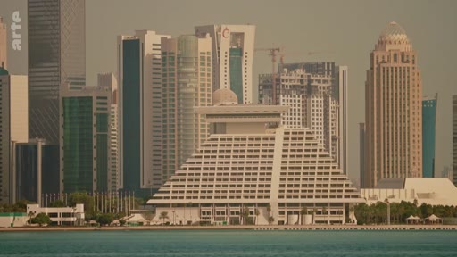 Vue d'ensemble de la skyline de Doha, capitale du Qatar, mettant en avant l'architecture pyramidale caractéristique de l'hôtel Sheraton Doha au premier plan. Ce paysage urbain illustre le développement économique et architectural rapide de la ville dans le golfe Persique.