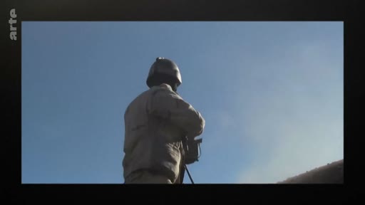 Un soldat en tenue de combat et casque militaire est filmé de dos, observant une zone extérieure sous un ciel dégagé. Cette image illustre les opérations militaires sur le terrain.