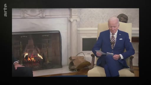 Le président américain Joe Biden est assis dans un fauteuil devant la cheminée du Bureau ovale à la Maison-Blanche, en train de consulter des documents.
