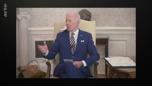 Le président américain Joe Biden est assis dans un fauteuil, gesticulant lors d'une interview dans un bureau officiel, probablement à la Maison Blanche.