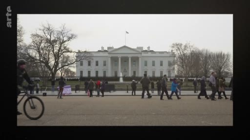Vue d'ensemble de la Maison Blanche à Washington D.C. avec des piétons et un cycliste circulant devant le bâtiment emblématique. Le site est un lieu de rassemblement fréquent pour les touristes et les manifestants.