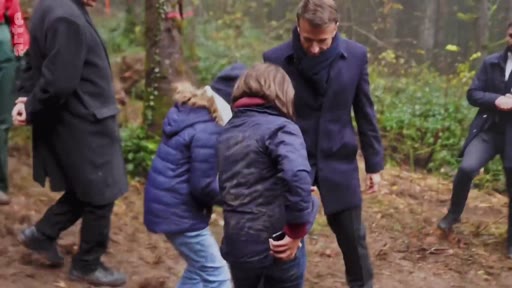 Le président français Emmanuel Macron lors d'un déplacement officiel dans une zone forestière, s'entretenant avec des personnes sur le terrain dans le cadre d'une initiative de reforestation.