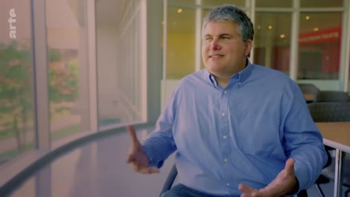 Un homme s'exprime lors d'une interview dans un bureau lumineux, discutant probablement des enjeux liés aux plantations industrielles d'arbres et aux forêts naturelles.