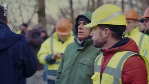 Des travailleurs forestiers portant des casques de sécurité et des gilets haute visibilité sont réunis en extérieur pour une discussion professionnelle.