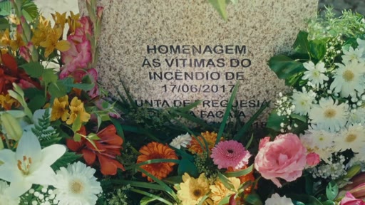 Une plaque commémorative en pierre entourée de fleurs rend hommage aux victimes de l'incendie survenu le 17 juin 2017, probablement à Pedrógão Grande au Portugal.
