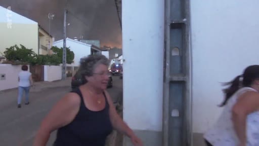 Des habitants évacuent une rue alors qu'un incendie fait rage en arrière-plan, créant une atmosphère de panique et de danger. Cette séquence d'amateur montre la détresse des riverains face à la progression des flammes.