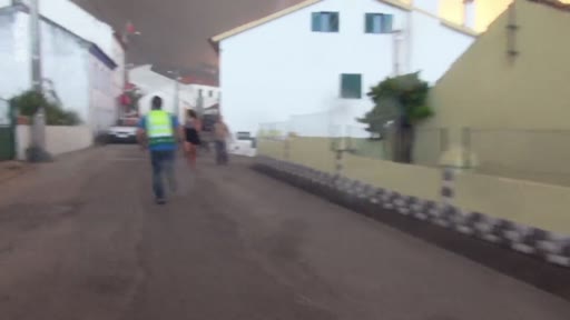 Des habitants évacuent en urgence une zone résidentielle menacée par un violent incendie de forêt, sous un ciel obscurci par les fumées. La scène montre des personnes courant dans la rue pour se mettre à l'abri.