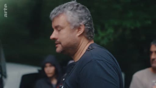 Un homme aux cheveux gris, possible militant ou intervenant, est filmé de profil lors d'une discussion en extérieur dans le cadre du mouvement d'éradication des eucalyptus.