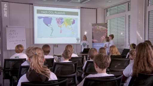 Des enfants membres de l'organisation Plant-for-the-Planet font une présentation devant un groupe de jeunes sur les enjeux climatiques, illustrée par une carte du monde montrant les émissions de CO2 par pays.