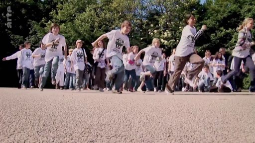 Un groupe d'enfants portant des t-shirts blancs court sur un chemin dans un parc, illustrant les activités de sensibilisation environnementale de l'organisation Plant for the Planet.