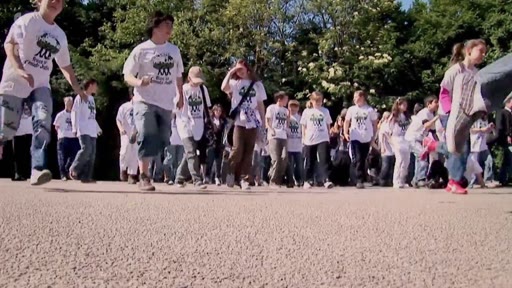 Un groupe de jeunes militants portant des t-shirts blancs avec le logo 'Plant for the Planet' marche ensemble lors d'un rassemblement en extérieur. Cette image illustre les actions de sensibilisation menées par l'organisation environnementale.