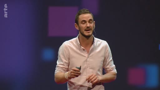 Un présentateur masculin s'exprime sur scène devant un fond sombre avec des motifs géométriques, lors d'une conférence sur les enjeux climatiques.