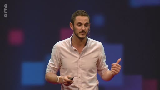 Un présentateur masculin s'exprime sur scène devant un écran sombre avec des motifs géométriques, illustrant une conférence sur les enjeux climatiques.