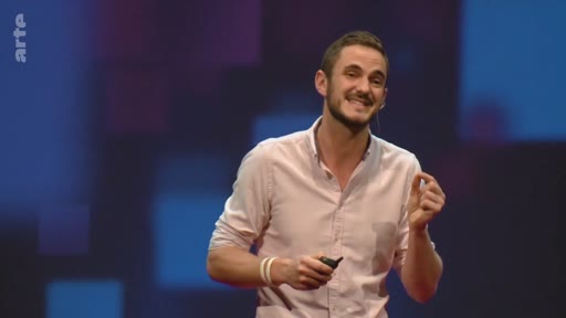 Un présentateur barbu en chemise rose s'exprime sur scène lors d'une conférence sur le potentiel de reforestation mondial.