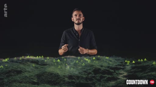 Un présentateur de l'émission Countdown sur Arte présente une analyse scientifique illustrée par une projection numérique de terrain parsemée de marqueurs triangulaires. Le visuel évoque une étude de données géographiques ou environnementales.
