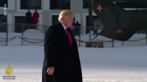 Donald Trump marche sur un sol enneigé à proximité d'un hélicoptère portant l'emblème de la Suisse. Cette image a été capturée lors d'un déplacement officiel, probablement à Davos.