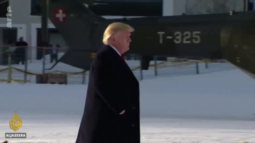 Donald Trump marche devant un hélicoptère de l'armée suisse portant l'immatriculation T-325 dans un environnement enneigé, probablement lors du Forum économique mondial de Davos.
