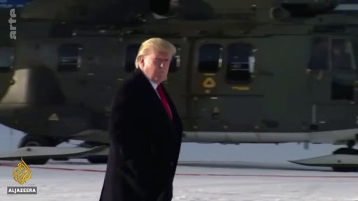 Donald Trump marche sur un tarmac enneigé devant un hélicoptère militaire, probablement lors d'un déplacement officiel.