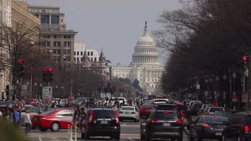 Vue extérieure du Capitole des États-Unis à Washington D.C. avec une circulation automobile dense au premier plan. Cette image illustre le siège du pouvoir législatif américain dans le contexte de débats politiques nationaux.