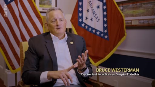 Le représentant républicain Bruce Westerman est interviewé devant les drapeaux des États-Unis et de l'Arkansas, discutant de sujets politiques liés à la reforestation.