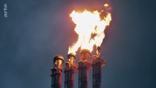 Vue en contre-plongée de quatre cheminées industrielles rejetant des flammes lors d'une opération de torchage de gaz, illustrant les pratiques polluantes de l'industrie pétrolière et gazière.