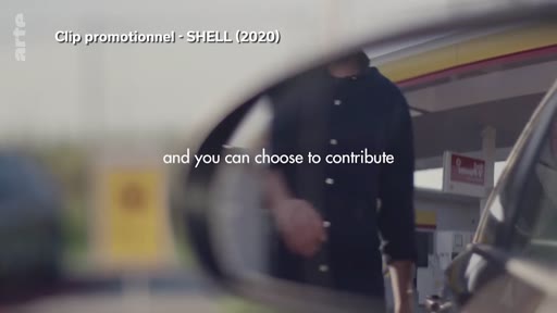 Un homme fait le plein de carburant dans une station-service Shell, une scène capturée dans un clip promotionnel de 2020. L'image est vue à travers le rétroviseur d'une voiture, illustrant les pratiques de communication de l'industrie pétrolière.