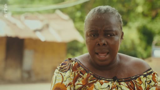 Une femme s'exprime face caméra lors d'un entretien en extérieur, évoquant les enjeux liés à la lutte pour les terres ancestrales. Elle porte un vêtement traditionnel à motifs dans un cadre rural.